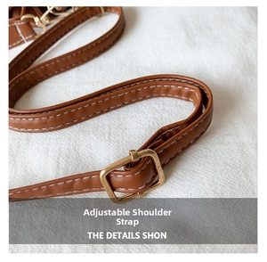 Detail of adjustable brown leather strap with gold buckle and white stitching