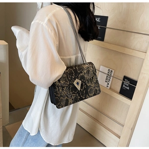 Detail of snake skin pattern texture with rhinestone chain strap on shoulder bag