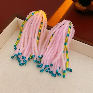 Boucles d'oreilles pompon en perles roses et vertes sur plateau vintage