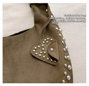 Detail of brown suede crescent bag featuring silver metal studs and a heart-shaped charm