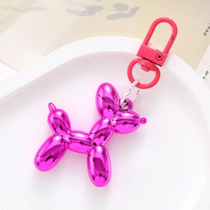 Pink metallic acrylic balloon dog keychain on a white tray with sleek silver chain