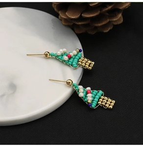 Detail of Christmas tree stud earrings with colorful beads on a marble plate
