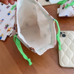 Macro view of drawstring cotton storage bag featuring bear prints and green woven cords