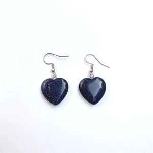Detailed view of heart-shaped blue sandstone drop earrings with silver hook on white background