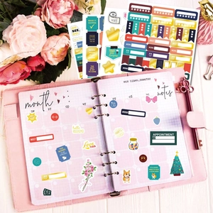 Flat lay of colorful planner stickers in a pink leather notebook with floral accents