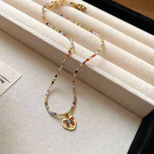 Elegant beaded necklace with a golden butterfly pendant on a soft velvet jewelry tray