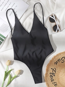 Deep V-neck black one-piece swimsuit shown with summer hat and sunglasses on fabric