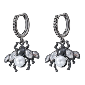 Macro shot of bee earrings with black metal, white pearls and sparkling crystal details