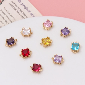 Macro shot of colorful square zircon charms with gold metal connectors on a plate