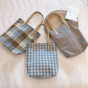 Detail of vintage plaid canvas tote bags with reinforced faux leather handles and rivets