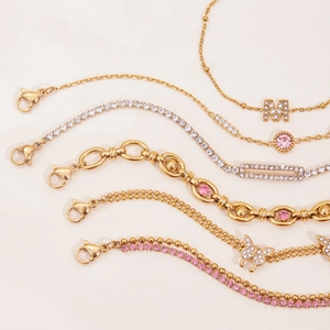 Detail of 18K gold plated bracelets with pink zircon and butterfly pendant charms