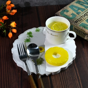 Unregelmäßiges Harz-Tablett mit grünen Pflanzen und Keramiktasse auf Holztisch