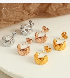Detailed close-up of C-shaped earrings with diamond quilted pattern in gold and silver
