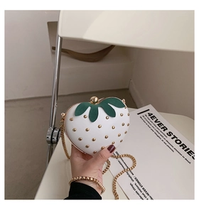 Close-up of white strawberry shaped mini bag with gold studs and chain strap