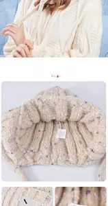 Close-up of beige knit beanie showing woolen texture, colorful dots, and care label details