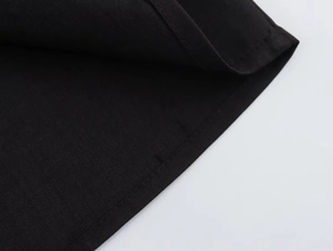 Détail macro des coutures impeccables et de la texture du tissu sur une robe moulante noire