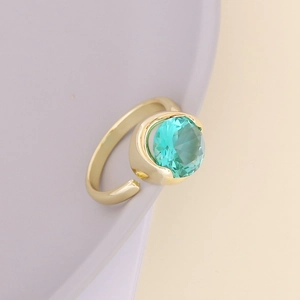 Detail of adjustable gold ring featuring a large faceted round turquoise zircon stone