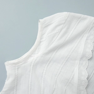 Close-up of white blouse featuring vertical jacquard texture and scalloped lace trim details