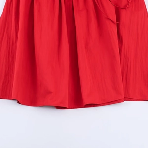 Close-up of bright red midi dress hem showing high-quality woven fabric texture and stitching
