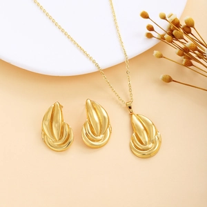 Detail of a golden jewelry set featuring layered curved earrings and a matching necklace