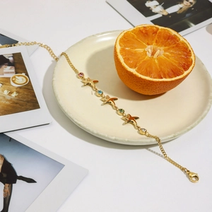 Starfish 18K gold plated bracelet with colorful cubic zirconia on a fresh orange plate