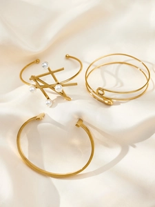 Close-up of three 18k gold plated geometric bracelets with pearls and safety pin details