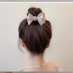 Rear view of cream satin bow hair claw clip styled on a classic bun hairstyle