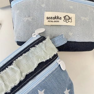Detail of denim patchwork makeup bag featuring star prints and woven puppy logo tag