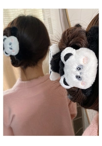 Detailed close-up of a cute plush panda hair claw clip worn on a girl's hairstyle