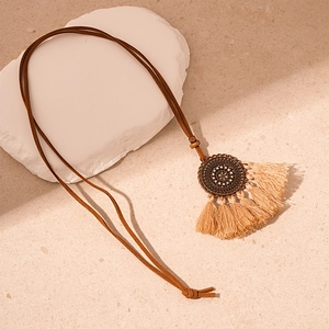 Close-up of vintage hollow floral pendant with soft beige tassels on stone base