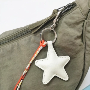 Star-shaped leather charm with white stitching on an olive green nylon bag