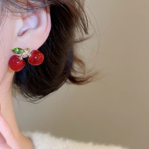 Detailed macro view showing the glossy resin cherry stud earrings with gold leaf accents