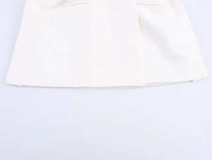 Detailed close-up of white twill fabric texture and stitching on the hem of the garment