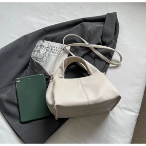 Flat lay of cream lychee texture handbag with shoulder strap on a grey suit and white cloth