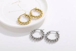 Detailed view of gold and silver beaded hoop earrings on a decorative ceramic plate