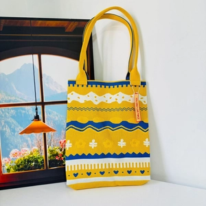 Close-up of yellow knit tote bag featuring blue and white geometric heart patterns