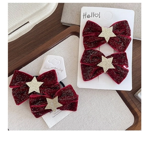 Detail of red velvet bow hair clips with glittering gold stars on display cards