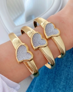 Detail showing a gold-plated heart bracelet with pavé cubic zirconia worn on a wrist