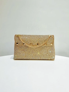 Detail of shimmering gold rhinestone swirl pattern and gold chain strap on dinner bag