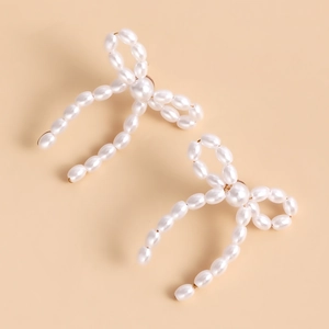 Detailed view of handmade woven faux pearl bow earrings with natural luster