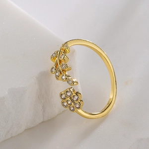 18K gold plated flower and leaf ring with zircon accents on a textured stone surface