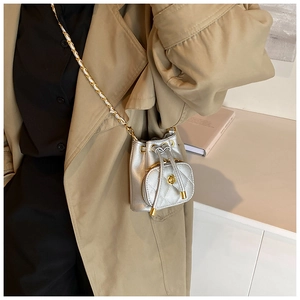 Detail of silver bucket bag with quilted pocket, chain strap, and floral metal buckle