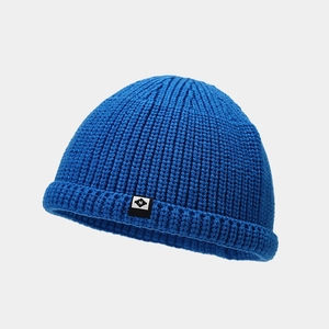 Gros plan du bonnet en tricot bleu roi montrant la texture côtelée et l'étiquette tissée