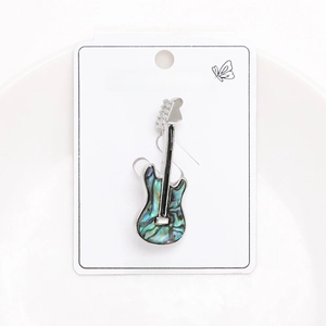 Macro d'une broche guitare argentée avec incrustation de nacre bleue sur carte