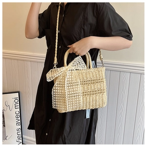 Detail view of beige straw handbag with white lace bow and woven shoulder strap