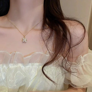 Detail shot of a gold clover necklace with crystal inlay on a model's neck for elegant styling