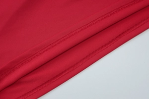 Gros plan de l'ourlet rouge montrant la couture surjetée fine et la texture du tissu de qualité