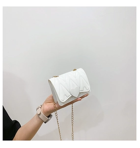 Close-up of pearl white quilted silicone mini bag with heart clasp and gold chain