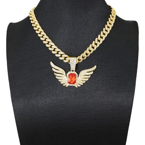 Macro shot of hip hop angel wing pendant with red gemstone on golden cuban link chain