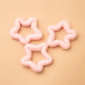 Three soft pink plush star ornaments for newborn photography on light beige background